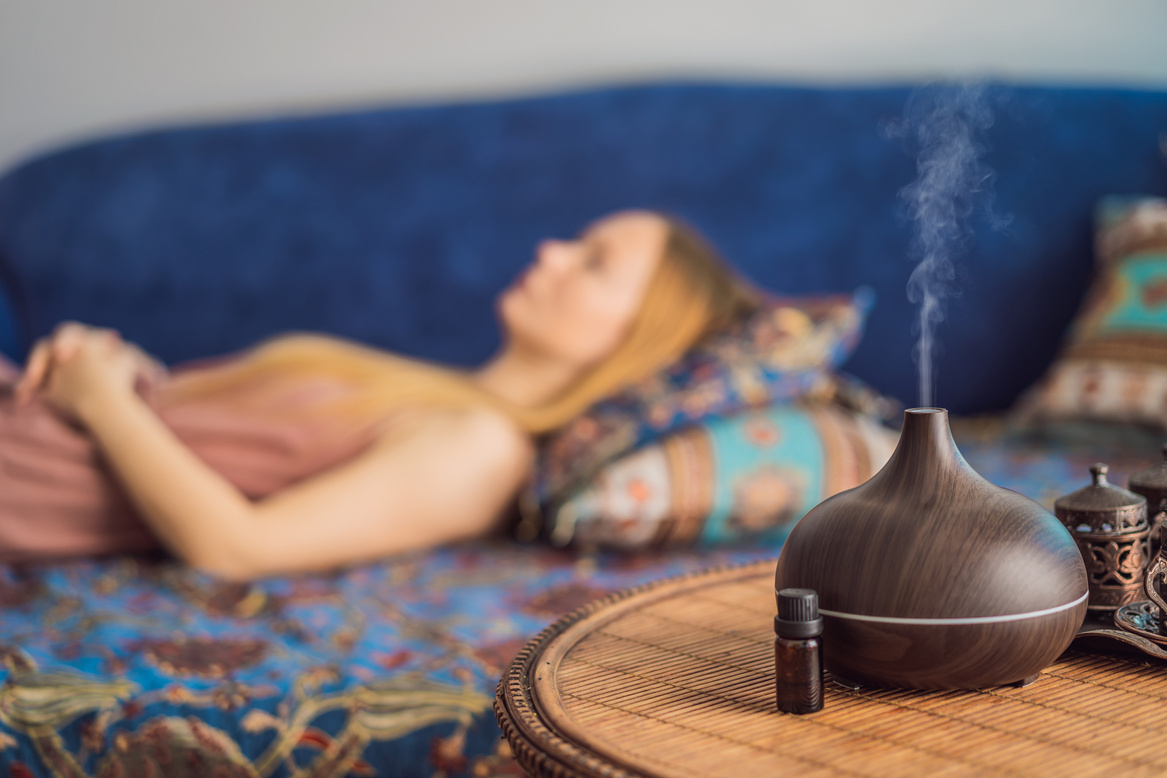 Aromatherapy Concept. Wooden Electric Ultrasonic Essential Oil Aroma Diffuser and Humidifier. Ultrasonic Aroma Diffuser for Home. Woman Resting at Home